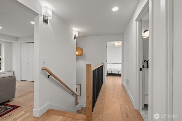 corridor featuring recessed lighting, light wood-type flooring, an upstairs landing, and baseboards