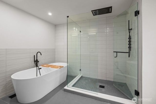 full bathroom with a shower stall, recessed lighting, tile walls, and a soaking tub