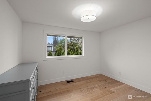 empty room featuring visible vents, baseboards, and light wood finished floors