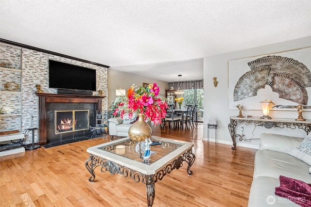 living area with a tile fireplace, a textured ceiling, baseboards, and wood finished floors