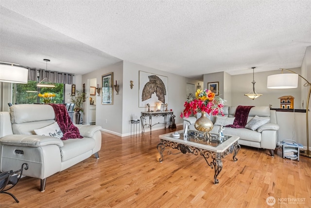 living room featuring a textured ceiling, wood finished floors, and baseboards