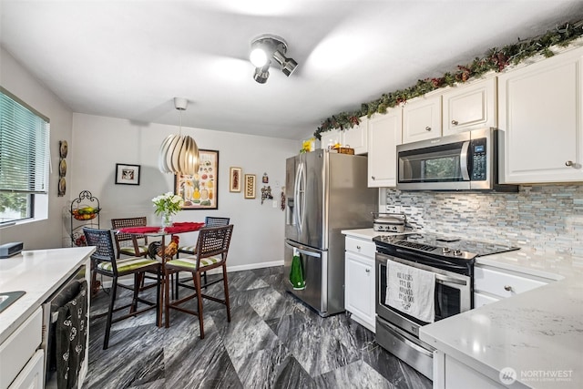 kitchen featuring tasteful backsplash, light countertops, appliances with stainless steel finishes, and white cabinetry