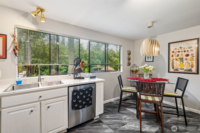 kitchen featuring light countertops, white cabinets, stainless steel dishwasher, pendant lighting, and a sink
