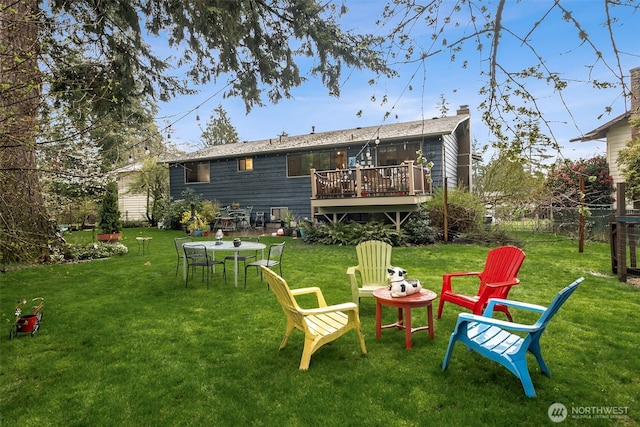 rear view of property with a yard, a deck, fence, and an outdoor fire pit
