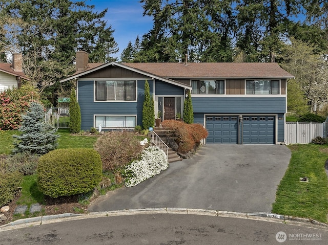 split foyer home featuring a chimney, driveway, a garage, and fence