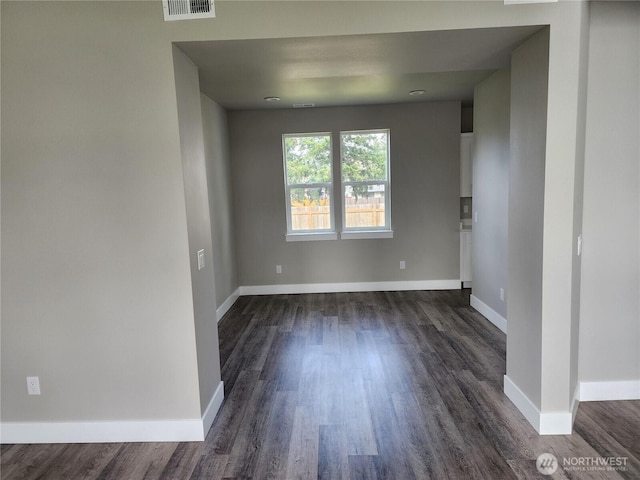 empty room featuring baseboards, visible vents, and dark wood finished floors