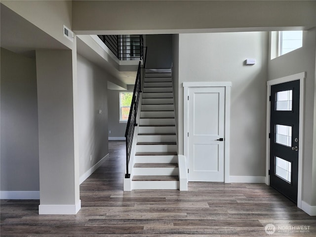 foyer featuring a high ceiling, baseboards, visible vents, and wood finished floors