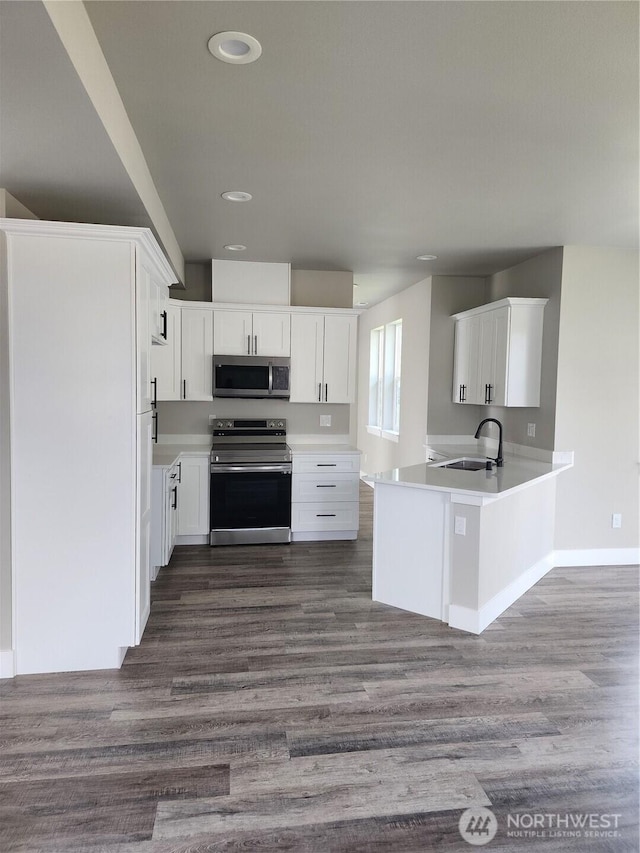 kitchen featuring white cabinetry, a sink, appliances with stainless steel finishes, and dark wood finished floors