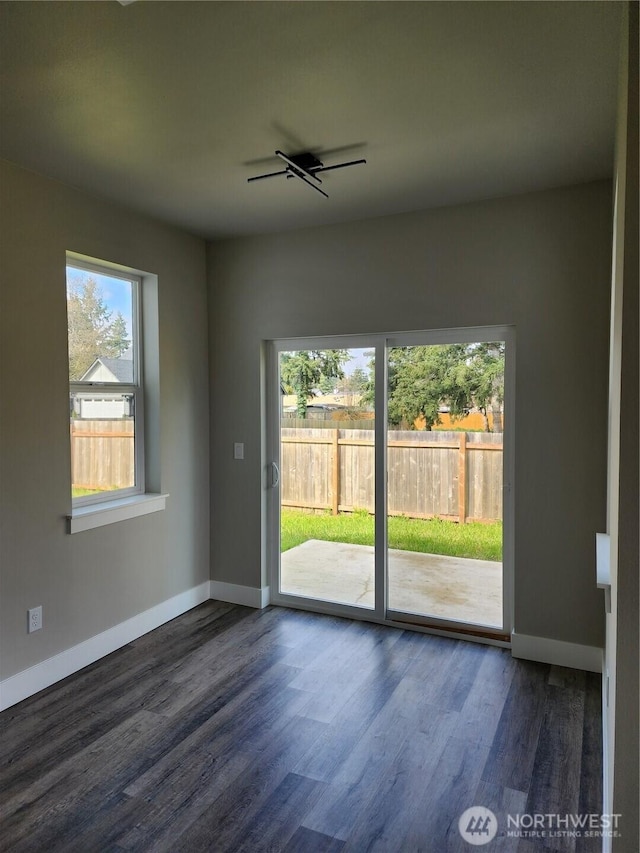 empty room with dark wood-type flooring and baseboards