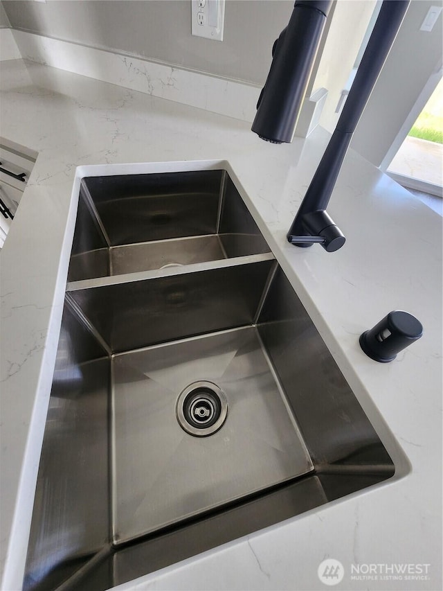 details featuring a sink and light stone counters