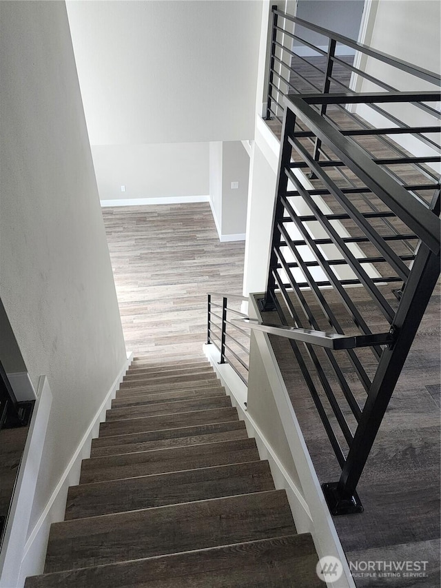 staircase with baseboards and wood finished floors