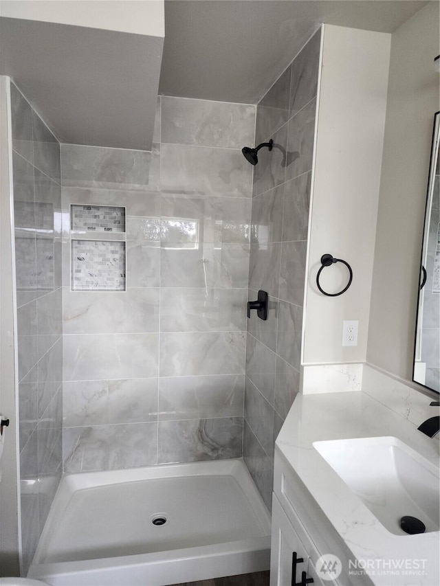 full bath featuring vanity and a tile shower