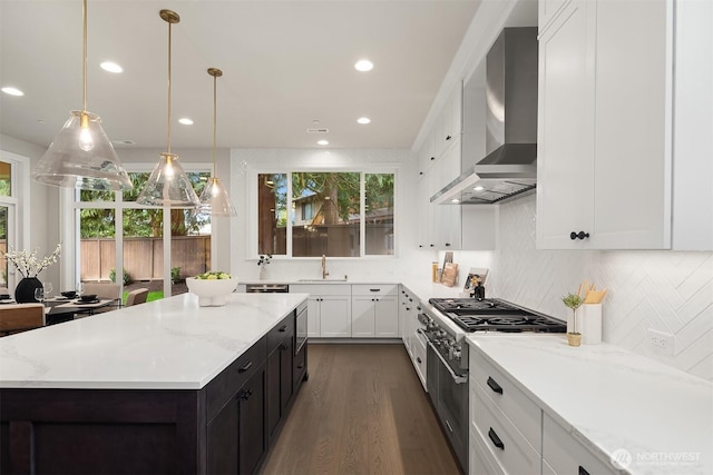 kitchen featuring white cabinets, a sink, high end stainless steel range, wall chimney range hood, and a center island