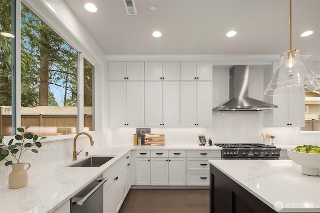 kitchen with white cabinetry, a sink, visible vents, dishwasher, and wall chimney exhaust hood