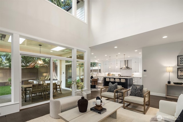 living area with baseboards, a high ceiling, recessed lighting, and dark wood-type flooring