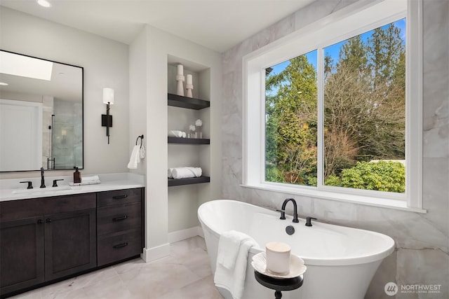 full bathroom with a wealth of natural light, a freestanding bath, built in features, and vanity