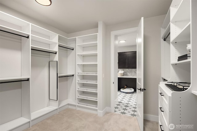 walk in closet featuring light colored carpet