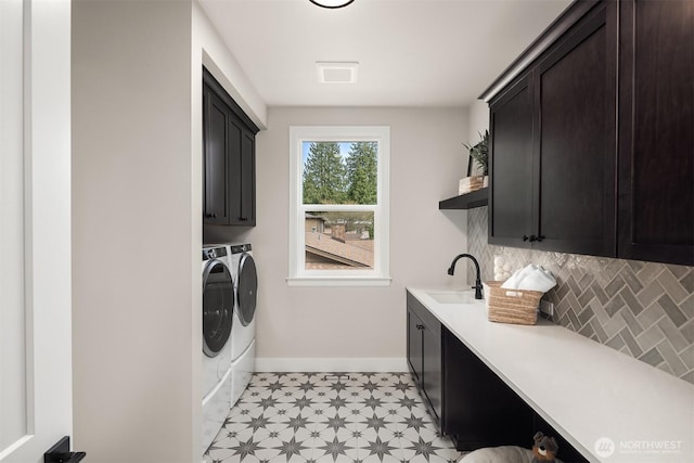 washroom featuring baseboards, light floors, a sink, cabinet space, and separate washer and dryer