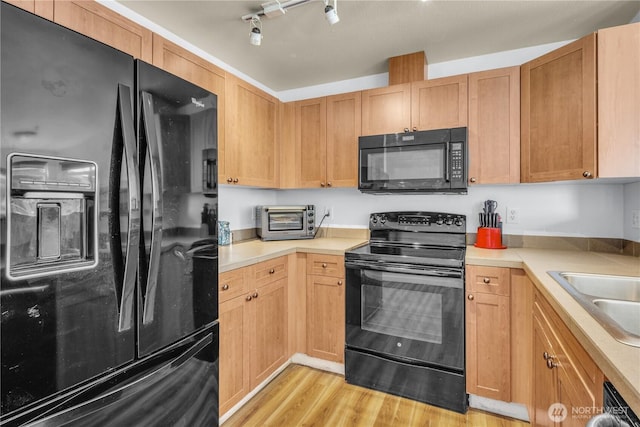500 Elliott Ave W Unit 309, Seattle, WA 98119 - kitchen featuring black appliances, light wood-style floors, light countertops, a sink, and track lighting
