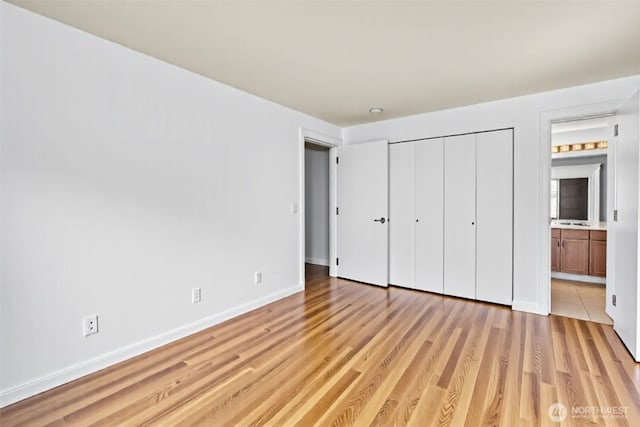 500 Elliott Ave W Unit 309, Seattle, WA 98119 - unfurnished bedroom featuring light wood-type flooring, baseboards, connected bathroom, and a closet