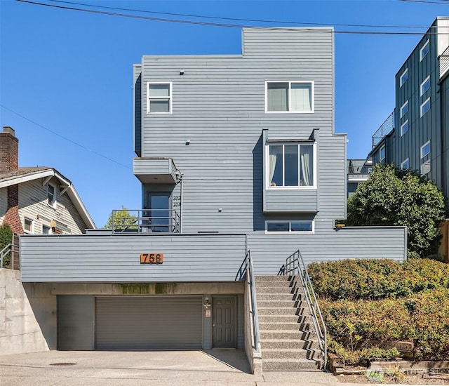 756 N 72nd St Unit 101, Seattle, WA 98103 - view of front of house with stairs, an attached garage, concrete driveway, and a balcony