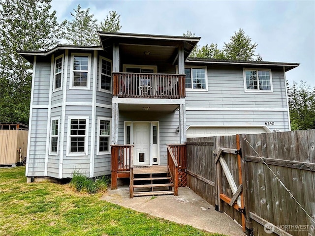rear view of property featuring a balcony, a deck, and a gate