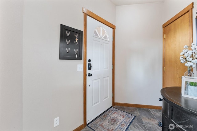 foyer entrance featuring baseboards and stone finish flooring