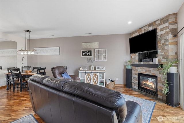 living area featuring recessed lighting, visible vents, a stone fireplace, and light wood finished floors