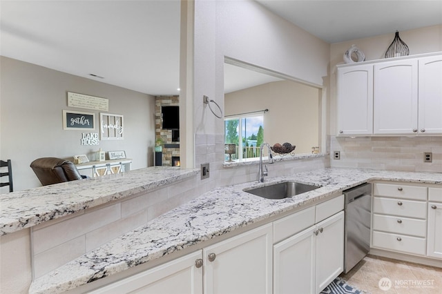 kitchen featuring a sink, light stone counters, decorative backsplash, and stainless steel dishwasher