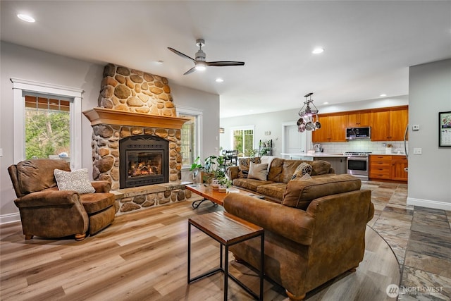 living room with a stone fireplace, recessed lighting, a wealth of natural light, and a ceiling fan
