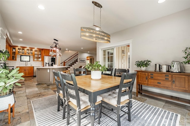 dining room featuring stairway, recessed lighting, arched walkways, and stone tile floors