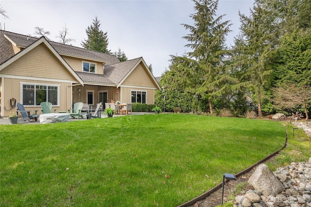 rear view of property featuring board and batten siding, a shingled roof, a yard, and a patio area
