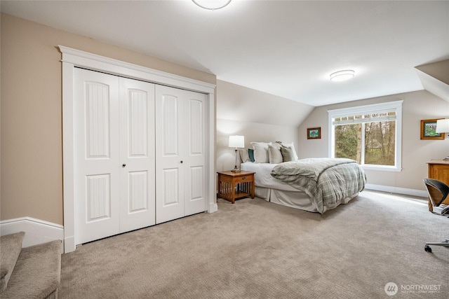 carpeted bedroom featuring a closet, baseboards, and vaulted ceiling