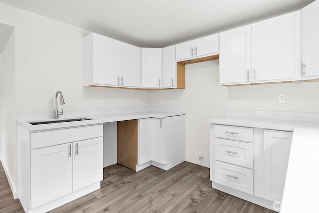 kitchen featuring light countertops, white cabinets, a sink, and light wood finished floors