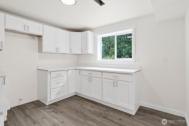 kitchen with baseboards, white cabinets, wood finished floors, and light countertops