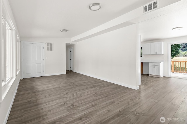 interior space featuring baseboards, visible vents, and wood finished floors