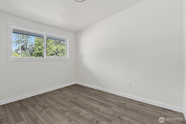 spare room with dark wood-type flooring and baseboards