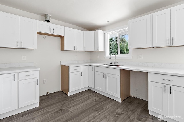kitchen featuring white cabinetry, light countertops, vaulted ceiling, a sink, and dark wood-style floors