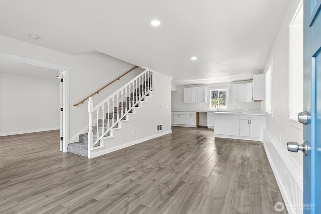 unfurnished living room featuring stairway, recessed lighting, baseboards, visible vents, and wood finished floors