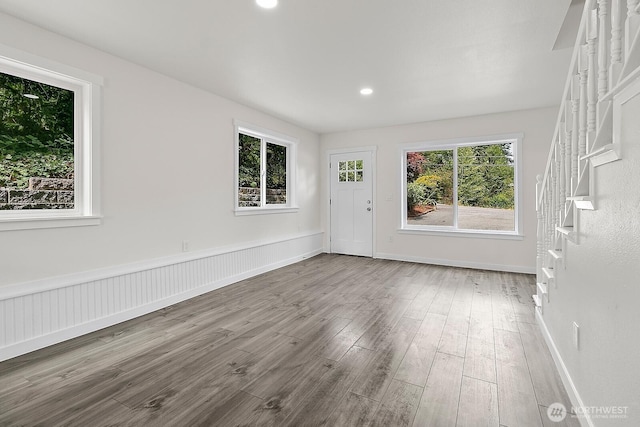 spare room featuring stairs, recessed lighting, baseboards, a wainscoted wall, and wood finished floors