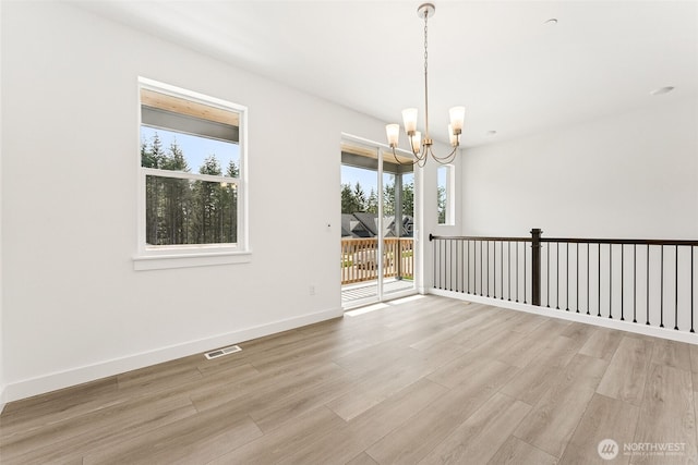 15710 210th Ave E Unit 311, Bonney Lake, WA 98391 - unfurnished room featuring healthy amount of natural light, a chandelier, light wood-style flooring, and baseboards