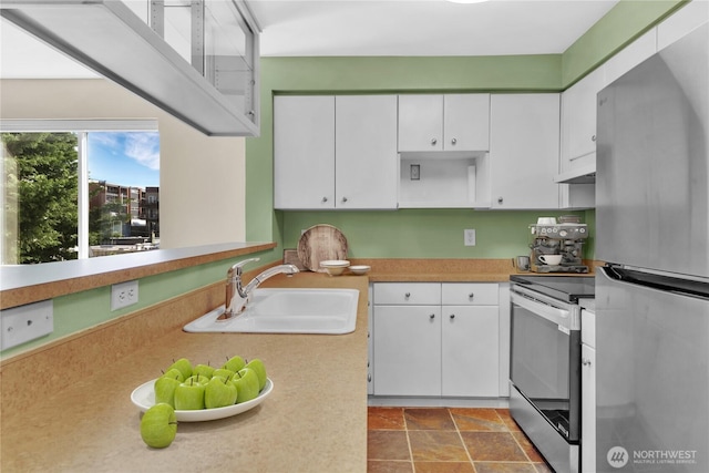 kitchen with light countertops, under cabinet range hood, white cabinets, a sink, and stainless steel appliances