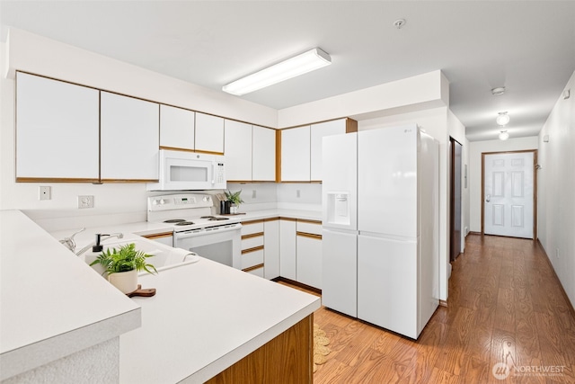 kitchen featuring white cabinets, light countertops, light wood-style floors, and white appliances
