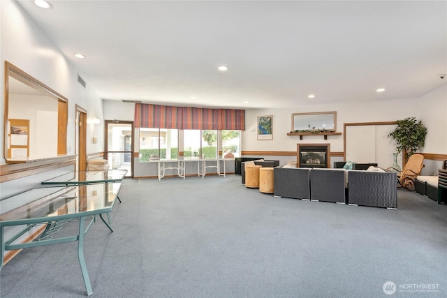 carpeted living area featuring visible vents, a glass covered fireplace, and recessed lighting