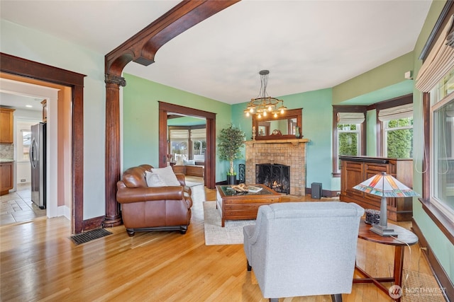 814 E Wright Ave, Tacoma, WA 98404 - living area with light wood-style flooring, a chandelier, and a brick fireplace