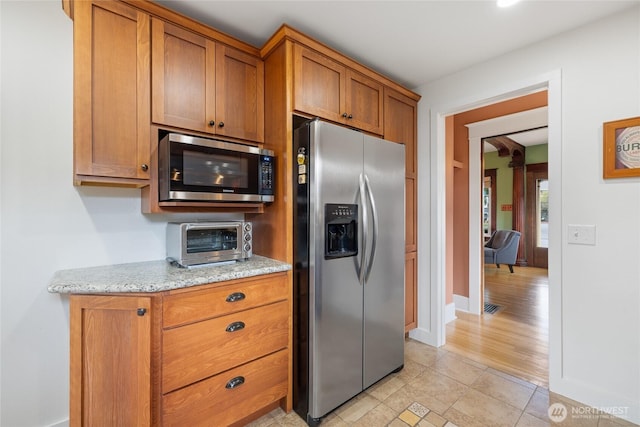 814 E Wright Ave, Tacoma, WA 98404 - kitchen with appliances with stainless steel finishes, brown cabinetry, and light stone countertops