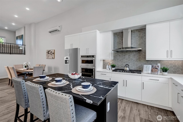 8818 NE 173rd Pl Unit B, Bothell, WA 98011 - kitchen featuring wall chimney range hood, appliances with stainless steel finishes, light wood finished floors, backsplash, and recessed lighting