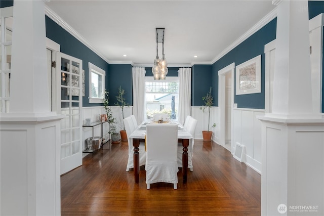 dining space with crown molding, a notable chandelier, wainscoting, and a decorative wall
