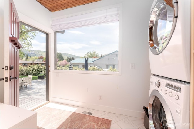 washroom featuring laundry area, baseboards, visible vents, a mountain view, and stacked washer and clothes dryer