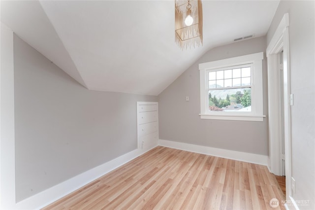 additional living space with baseboards, visible vents, wood finished floors, and lofted ceiling